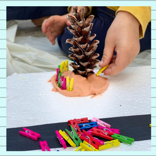 Turning a pine cone and clothespins into a tree with a fence around it